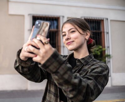 Ein Mädchen macht ein Selfie von sich und lächelt in die Kamera