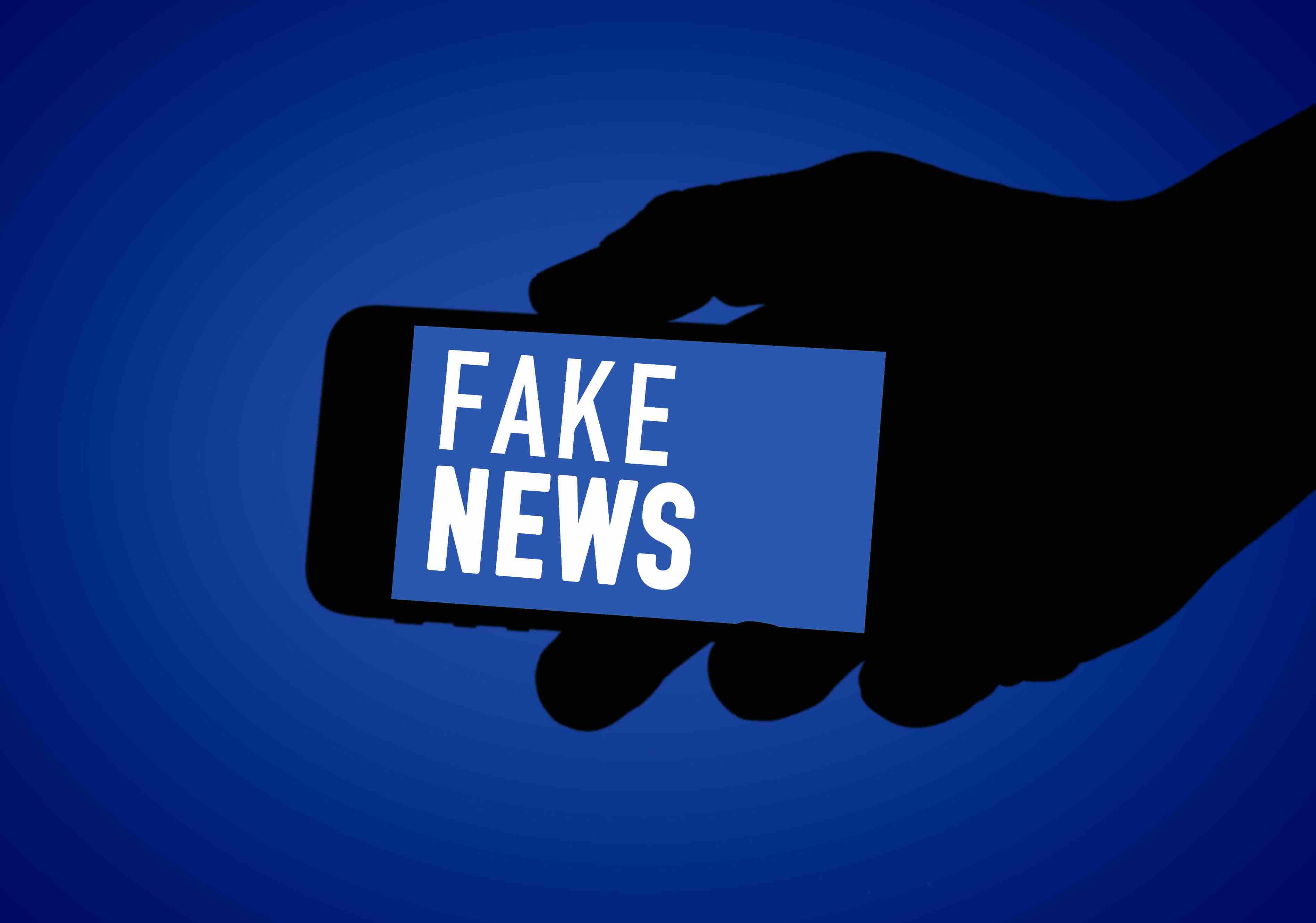 Fake News Eine Hand hält ein Smartphone, auf dem "Fake News" steht